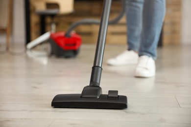 Photo of Young man using vacuum cleaner at home, closeup