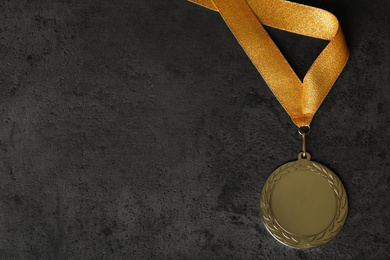 Photo of Gold medal on grey stone background, top view. Space for design