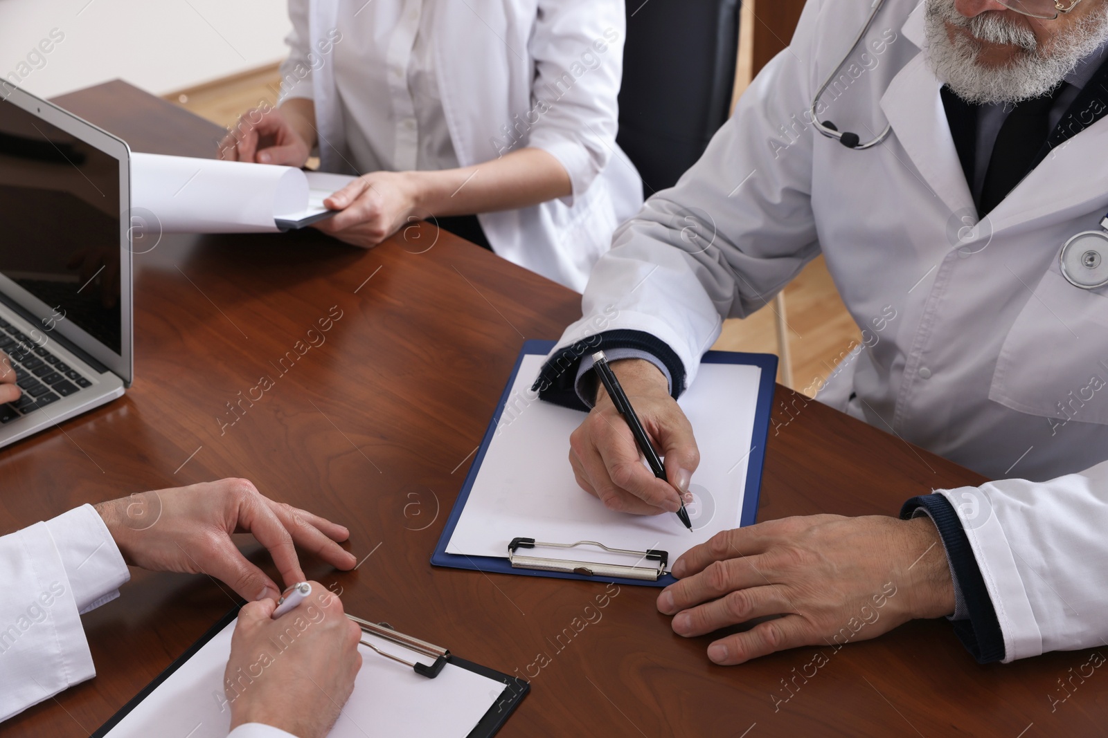 Photo of Team of doctors working with papers during medical conference indoors, closeup