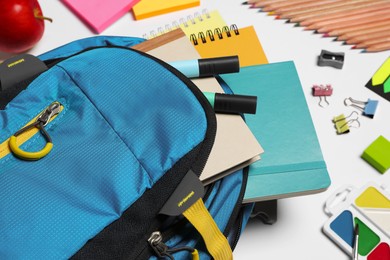 Backpack with different school stationery on white background