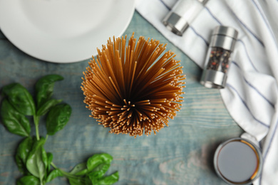 Uncooked buckwheat noodles and ingredients on blue wooden table, flat lay