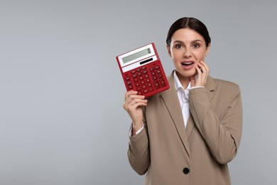 Photo of Emotional accountant with calculator on grey background, space for text