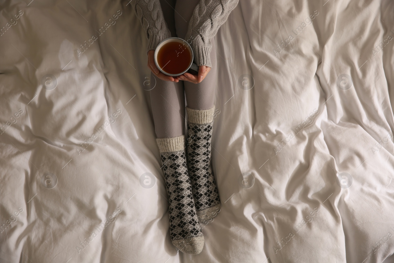 Photo of Woman with cup of tea on soft blanket, top view