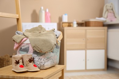 Photo of Laundry basket with baby clothes and shoes on wooden chair indoors, space for text