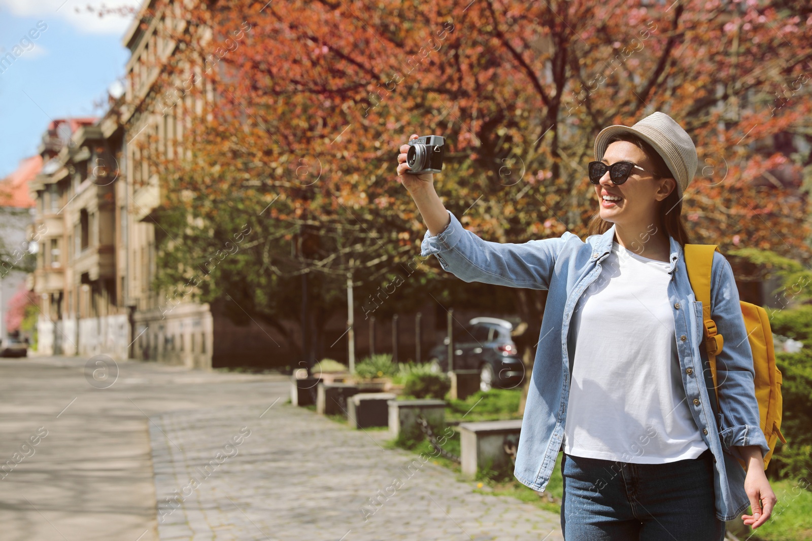 Photo of Happy female tourist with camera on city street