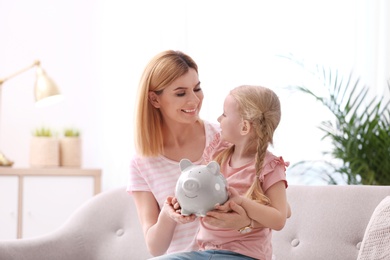 Mother and daughter with piggy bank at home