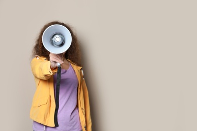 Photo of Young African-American woman with megaphone on color background. Space for text