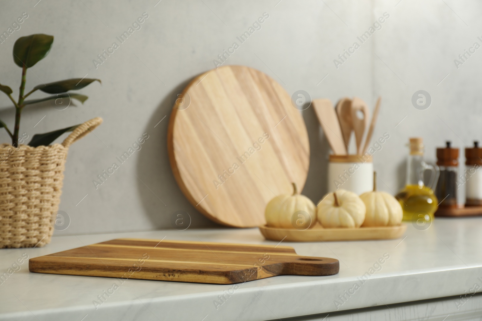 Photo of Wooden cutting board on white countertop in kitchen. Space for text