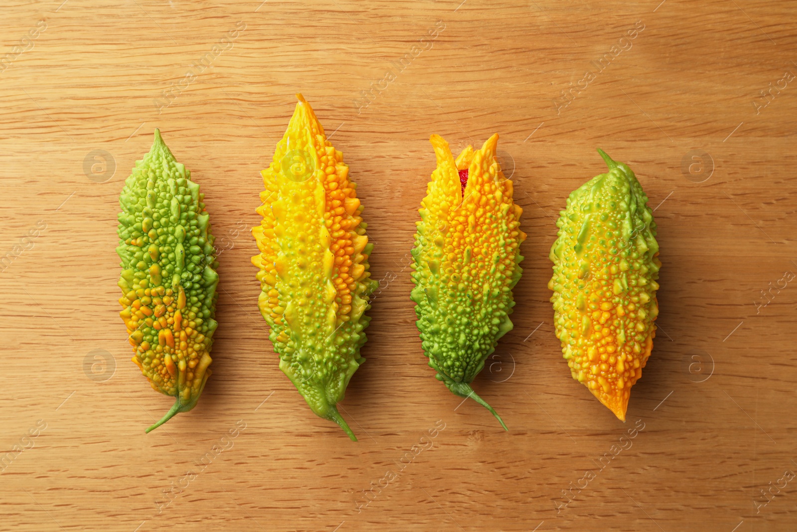 Photo of Fresh bitter melons on wooden table, flat lay