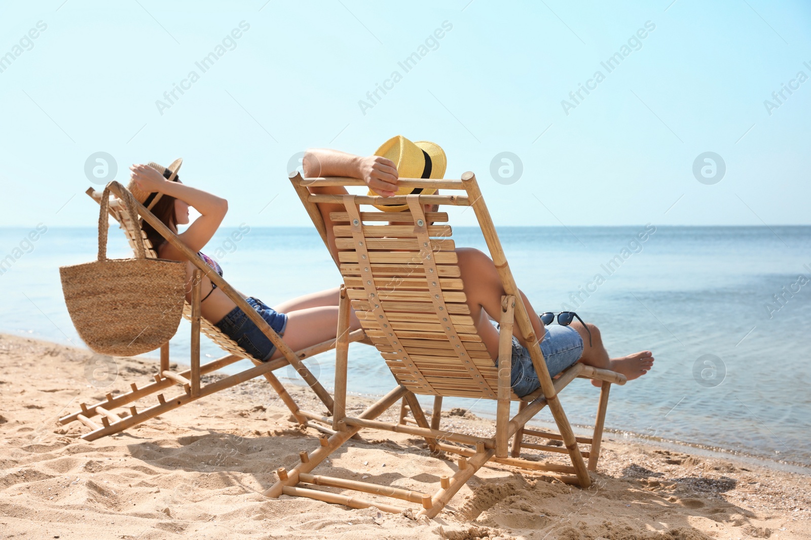 Photo of Young couple relaxing in deck chairs on beach