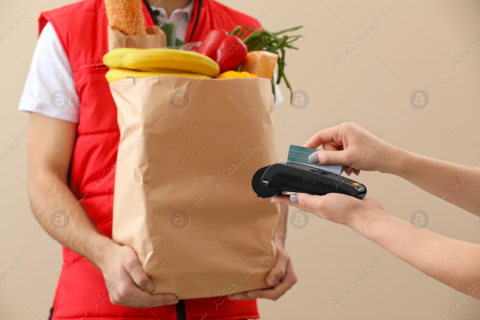 Photo of Customer using bank terminal to pay for food delivery on color background, closeup