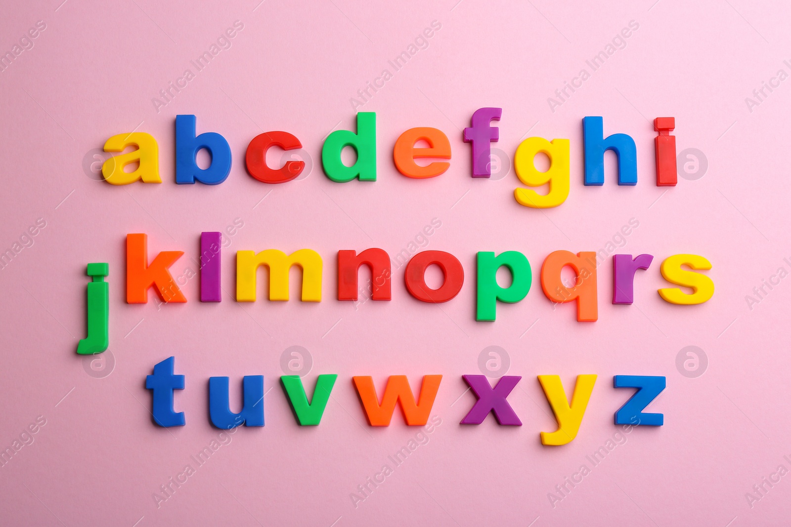 Photo of Plastic magnetic letters on pink background, flat lay. Alphabetical order