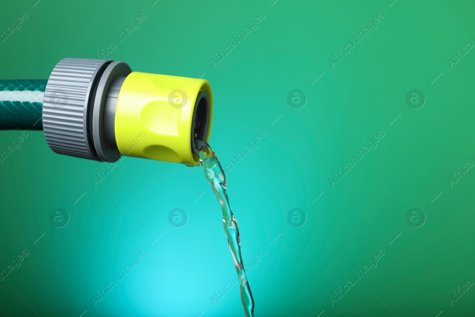 Photo of Water dripping from hose on green background, closeup. Space for text