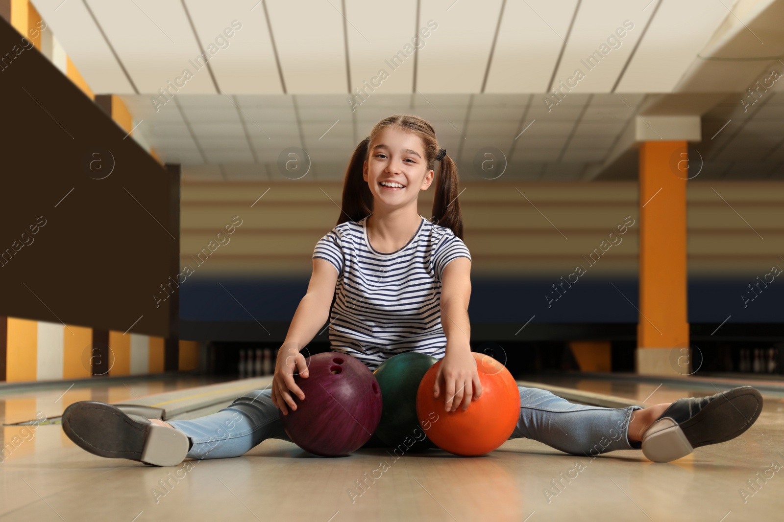 Photo of Preteen girl with balls in bowling club