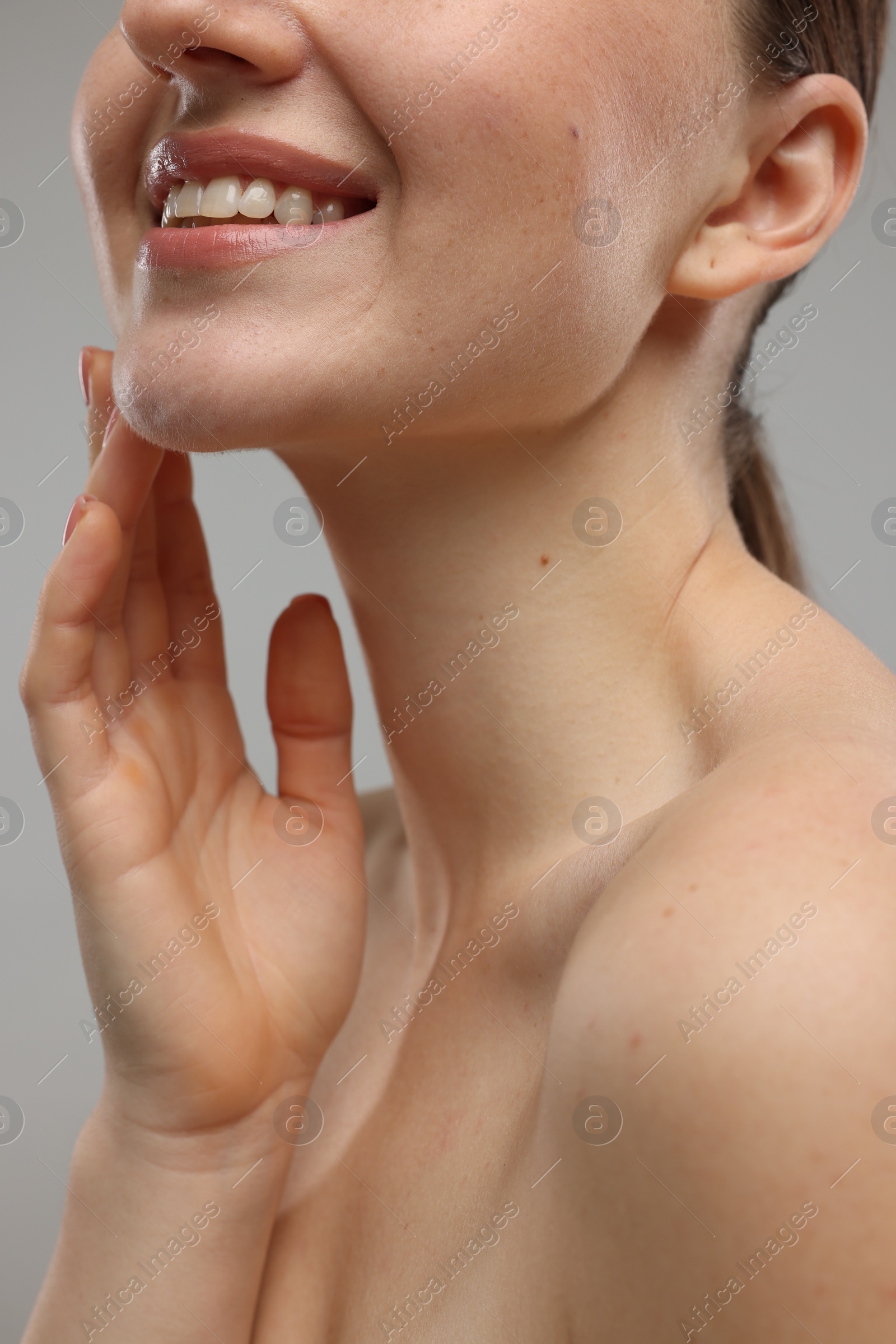 Photo of Smiling woman touching her chin on grey background, closeup