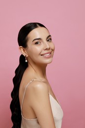 Photo of Young woman wearing elegant pearl earrings on pink background, space for text