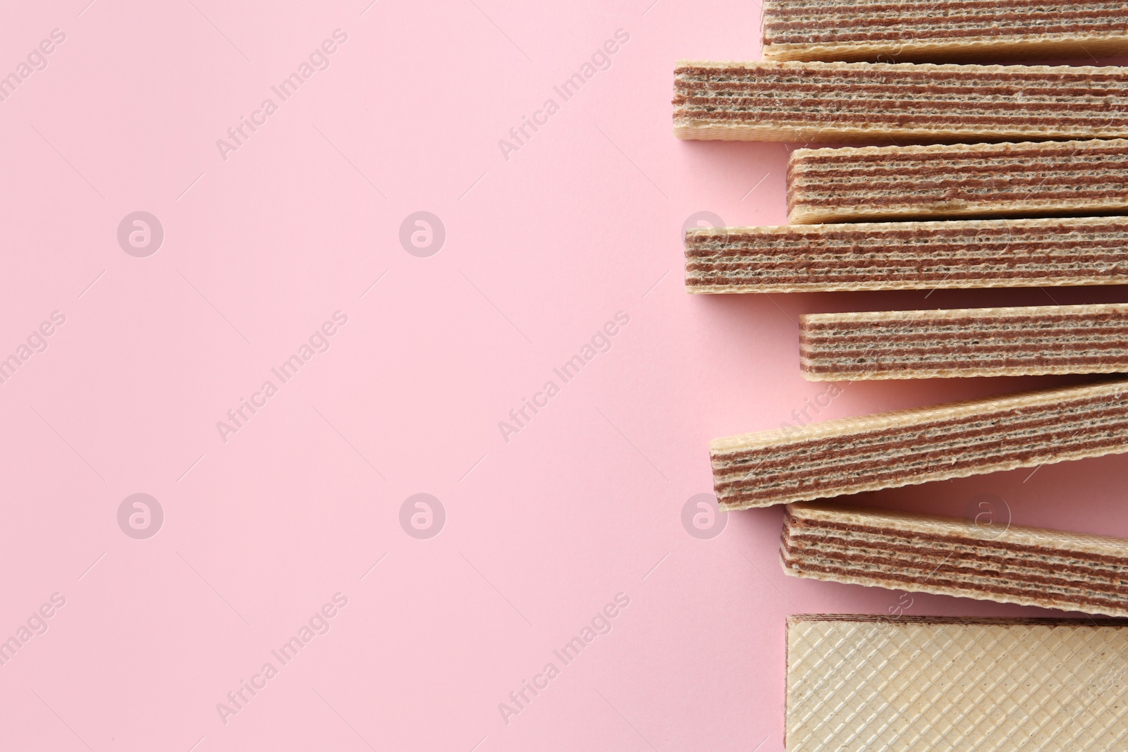 Photo of Tasty wafer sticks on pink background, flat lay with space for text. Sweet food