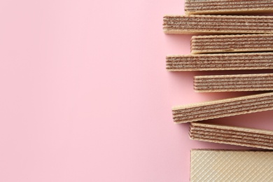 Tasty wafer sticks on pink background, flat lay with space for text. Sweet food