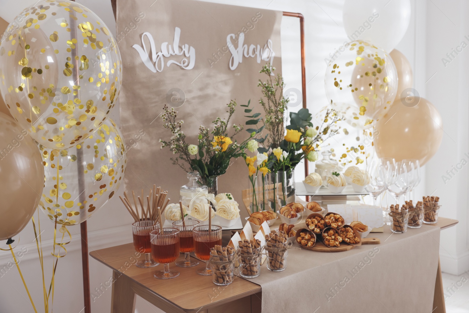 Photo of Tasty treats and glasses of drink on table in room. Baby shower party