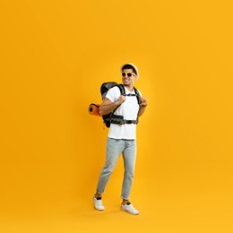 Photo of Male tourist with travel backpack on yellow background