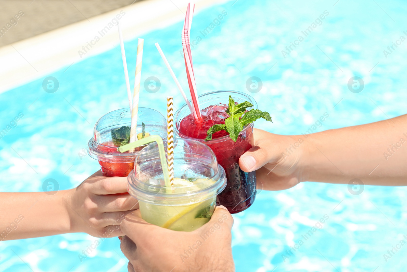 Photo of People with refreshing drinks in water park, closeup