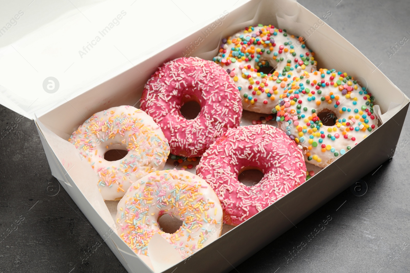 Photo of Sweet delicious glazed donuts on grey table