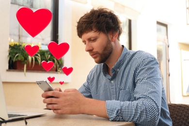 Image of Man visiting dating site via smartphone in cafe