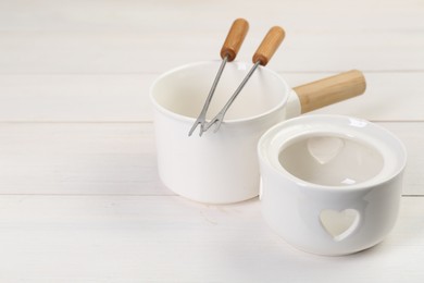 Photo of Fondue set on white wooden table, closeup. Space for text