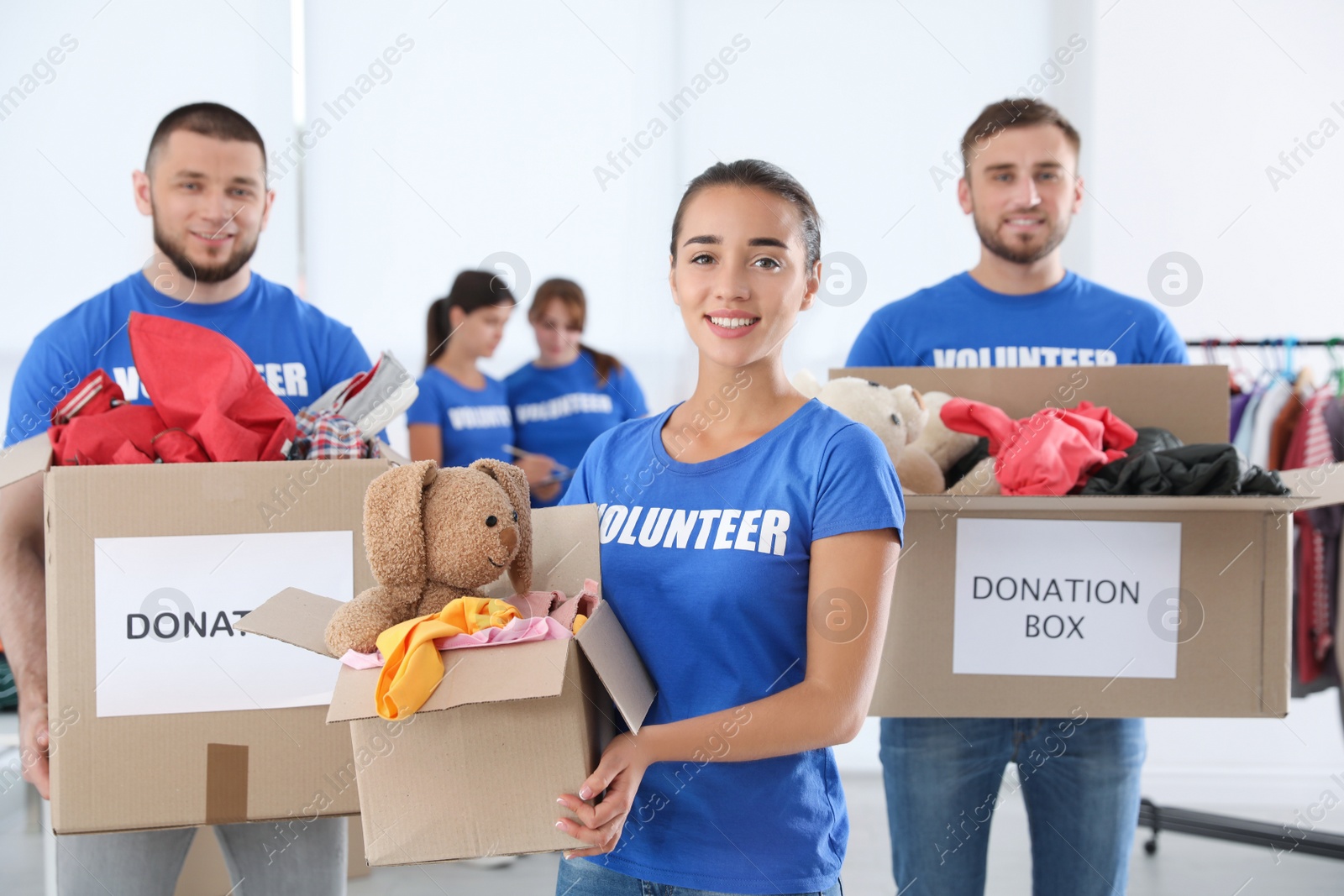 Photo of Young volunteers holding boxes with donations indoors