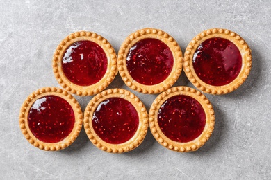 Photo of Tasty tartlets with jam on grey background