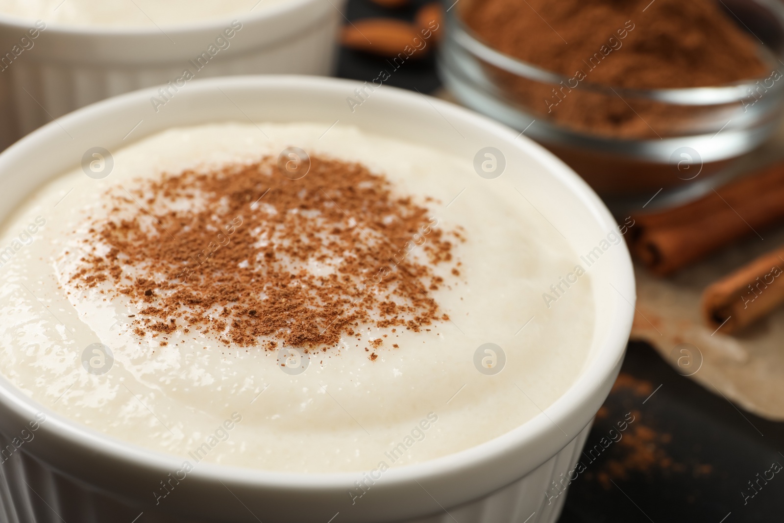 Photo of Delicious semolina pudding with cinnamon in bowl, closeup