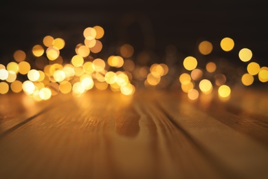 Photo of Empty wooden surface and blurred lights on background. Bokeh effect