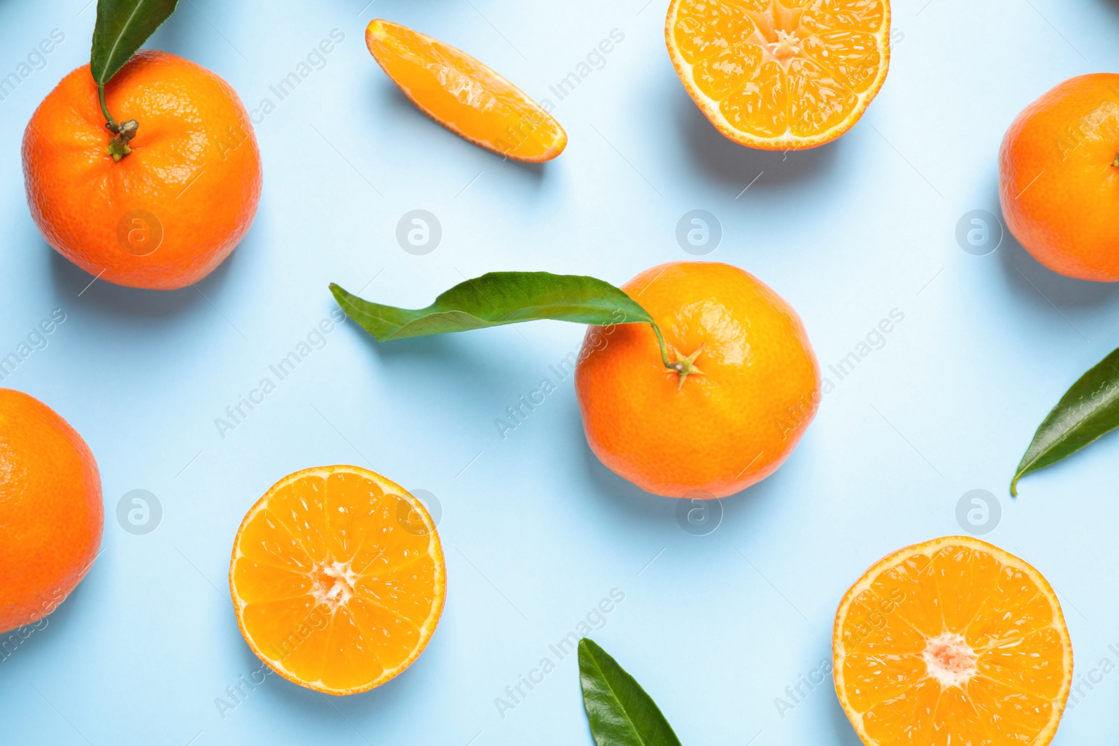 Photo of Flat lay composition with fresh ripe tangerines and leaves on light blue background. Citrus fruit