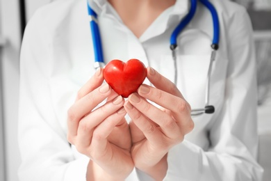 Photo of Doctor holding small red heart, closeup. Heart attack concept