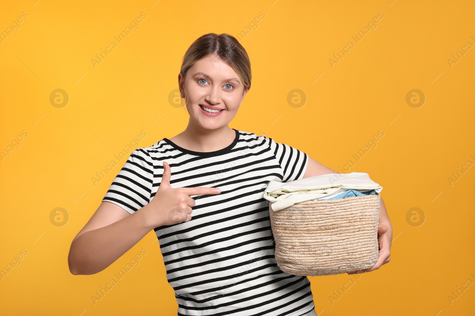 Photo of Happy woman with basket full of laundry on orange background