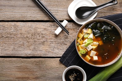 Bowl of delicious miso soup with tofu served on wooden table, flat lay. Space for text