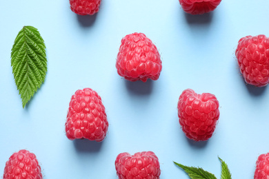 Photo of Fresh sweet ripe raspberries on light blue background, flat lay