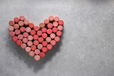 Photo of Heart made of wine bottle corks on grey table, top view. Space for text