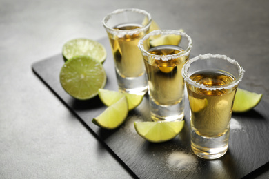 Mexican Tequila shots with salt and lime slices on grey table