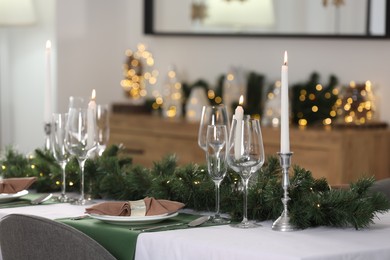 Christmas table setting with burning candles and festive decor in room