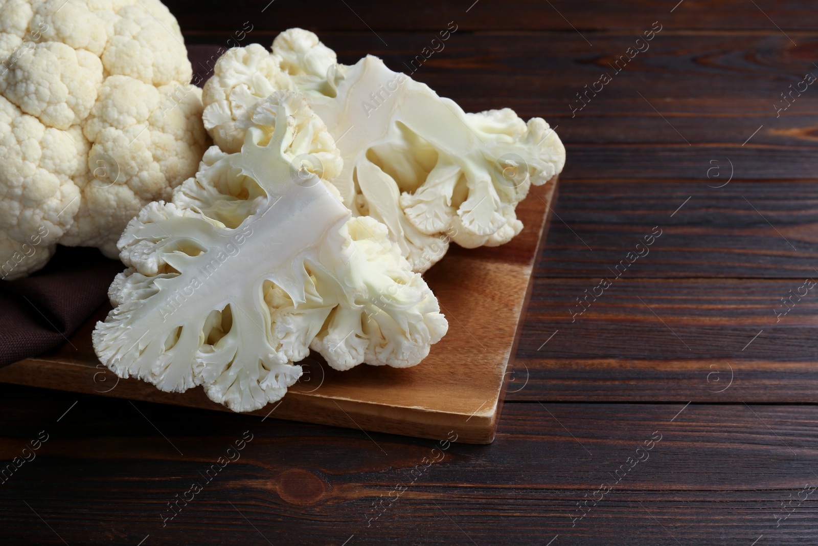 Photo of Fresh raw cauliflower on wooden table. Space for text