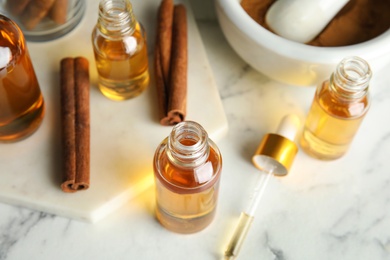 Photo of Bottles with essential oil and cinnamon sticks on marble table