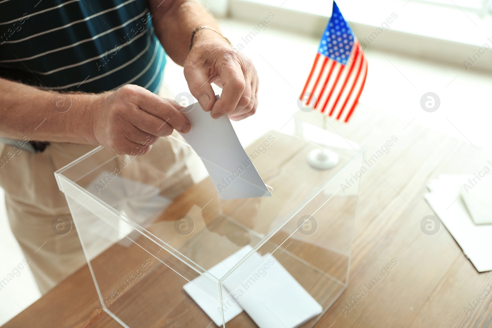 Photo of Elderly man putting ballot paper into box at polling station, closeup