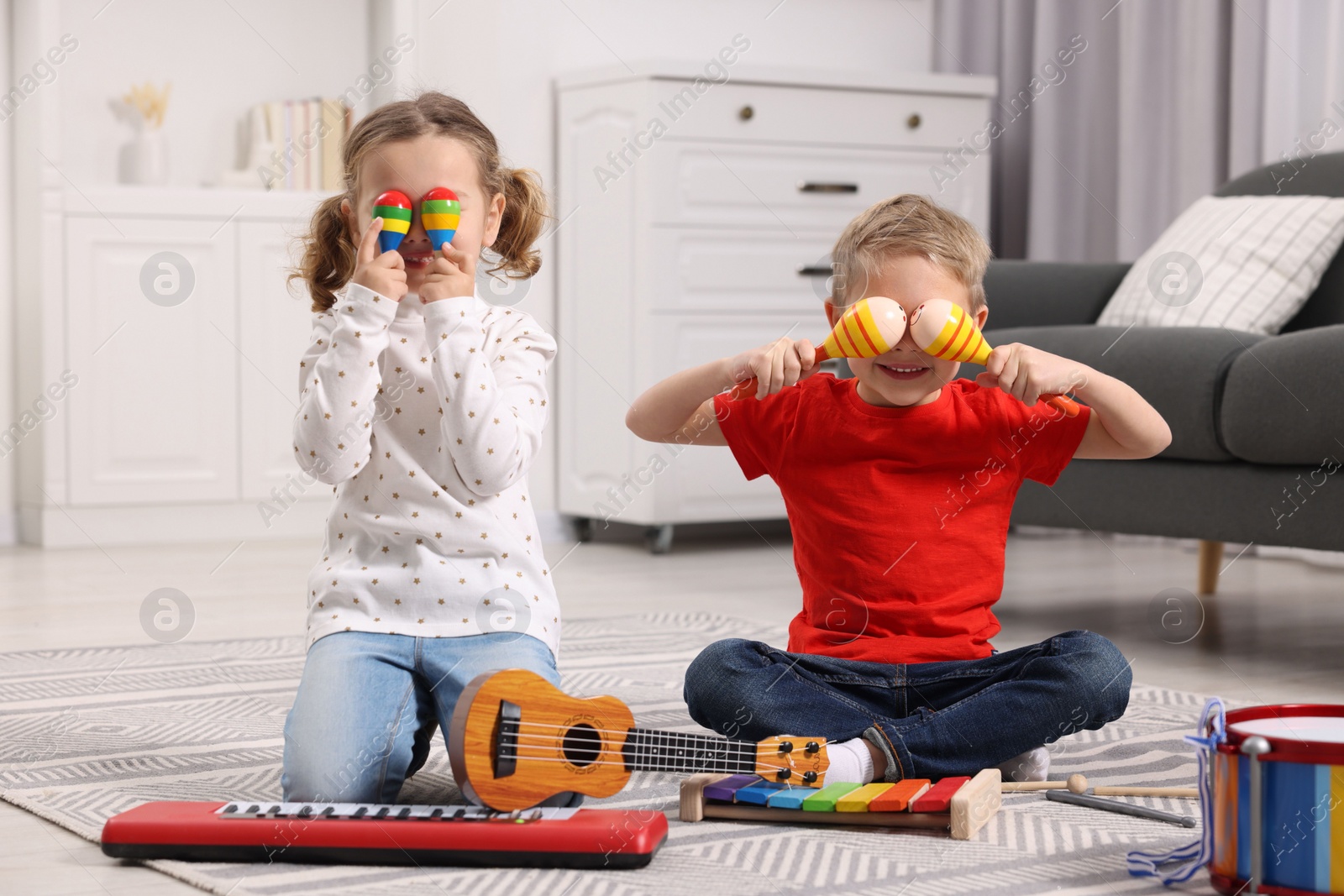 Photo of Little children playing toy musical instruments at home