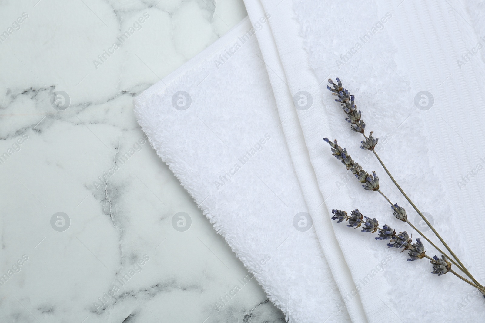 Photo of Terry towel and dry flowers on white marble table, top view. Space for text
