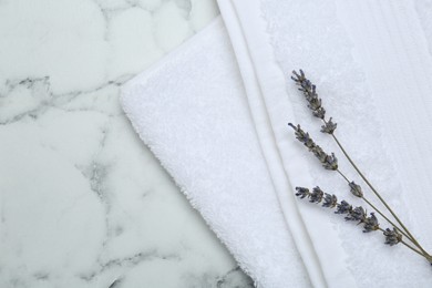 Terry towel and dry flowers on white marble table, top view. Space for text