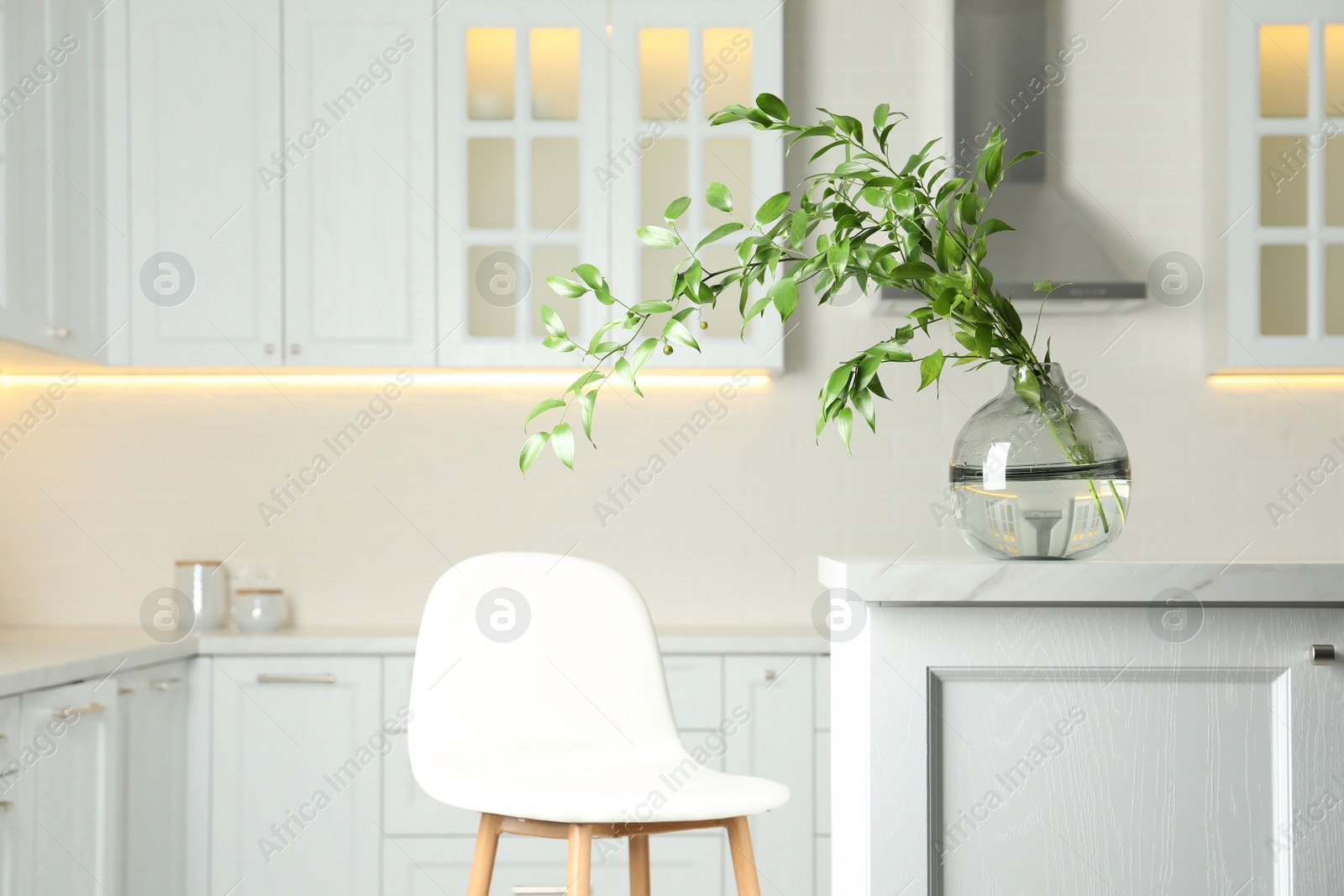 Photo of Decorative vase with branch on table in kitchen