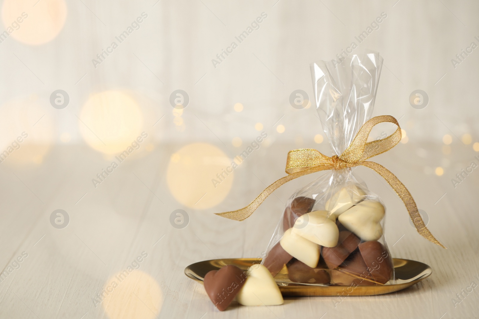 Photo of Heart shaped chocolate candies on white wooden table. Space for text