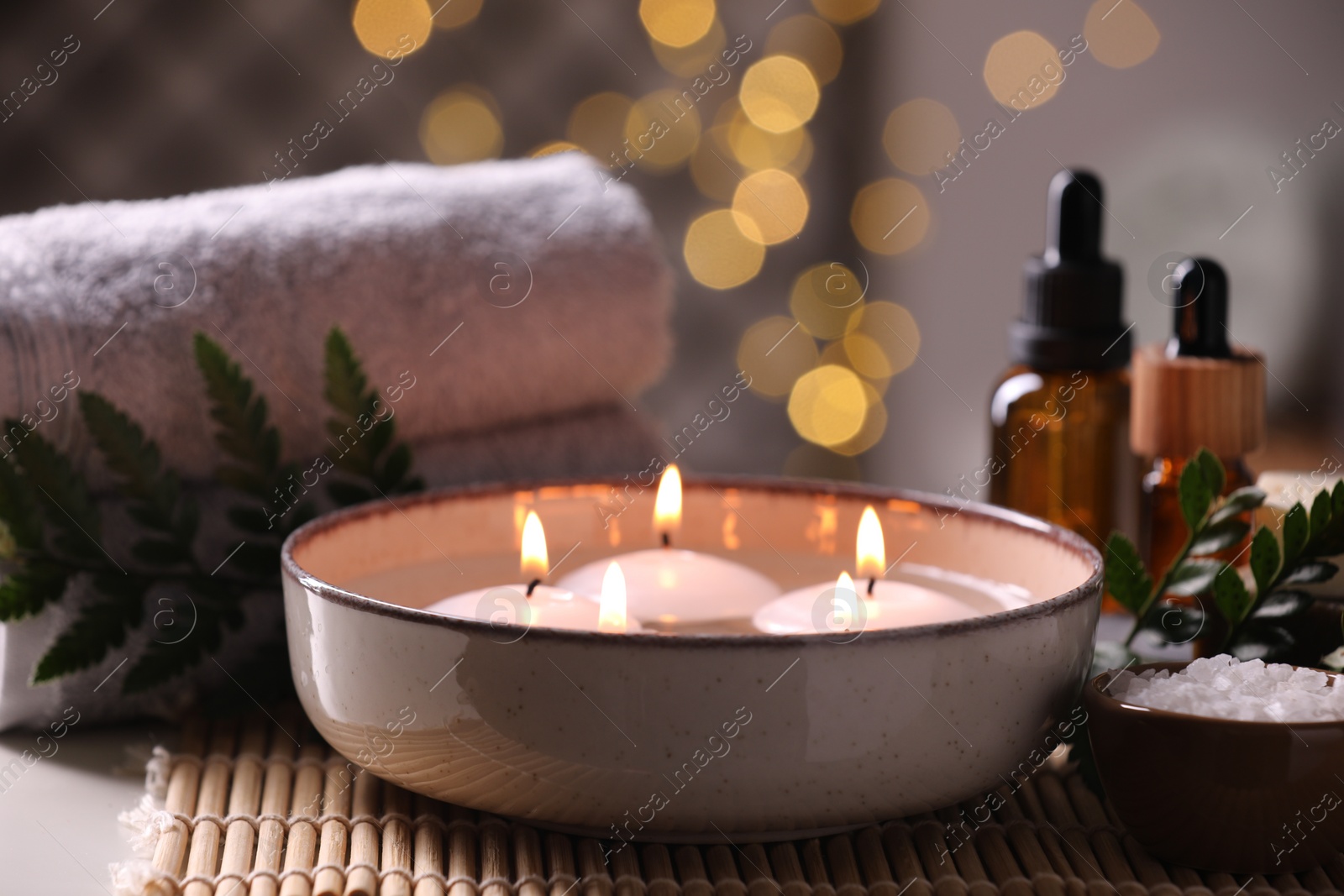 Photo of Beautiful composition with different spa products on table against blurred lights, closeup