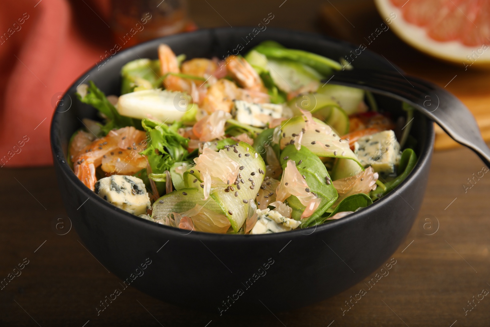 Photo of Delicious pomelo salad with shrimps served on wooden table, closeup